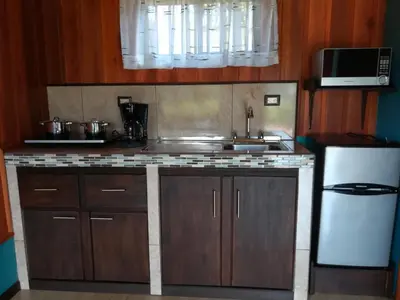 a kitchen with wooden cabinets and a sink and a refrigerator at Cabañas Sueños del Arenal in Fortuna