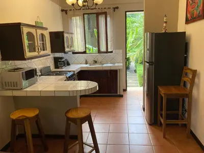 a kitchen with a counter and stools and a refrigerator at Casa Sueno Colibri in Tamarindo