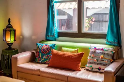 a couch with colorful pillows sitting under a window at ALAJUELA CITY Hotel & Guest House in Alajuela City