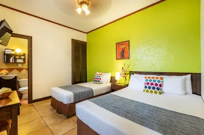 a room with two beds and a green wall at ALAJUELA CITY Hotel & Guest House in Alajuela City