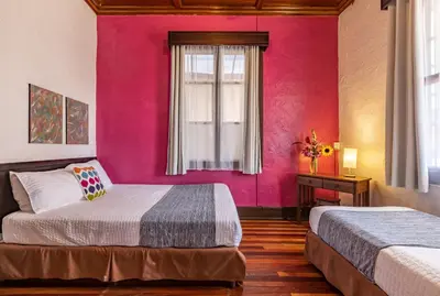 a bedroom with two beds and a pink wall at ALAJUELA CITY Hotel & Guest House in Alajuela City