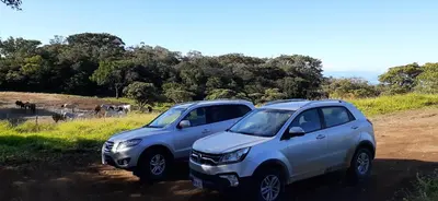 two cars parked on a dirt road in front of a field at Alojamientos Norte y Sur in Monteverde Costa Rica