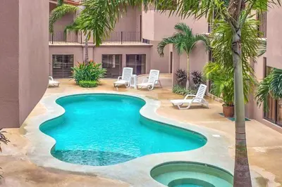 a swimming pool in the middle of a courtyard with palm trees at The Cove 3/4 in Coco