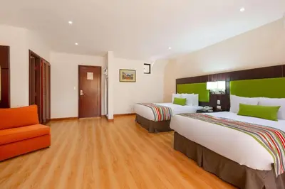 a hotel room with two beds and a chair at Country Inn & Suites by Radisson, San Jose Aeropuerto, Costa Rica in San José
