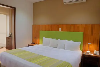 a bedroom with a large bed with a green headboard at Country Inn & Suites by Radisson, San Jose Aeropuerto, Costa Rica in San José