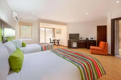a bedroom with a large white bed and an orange chair at Country Inn & Suites by Radisson, San Jose Aeropuerto, Costa Rica in San José