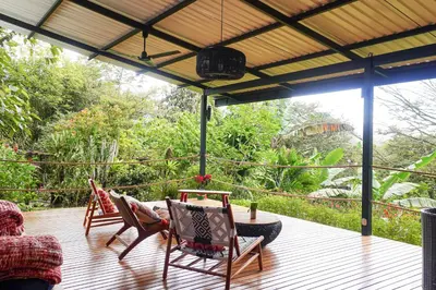 a patio with two chairs and a table on a deck at Sueño Río Celeste Boutique B&B in Bijagua