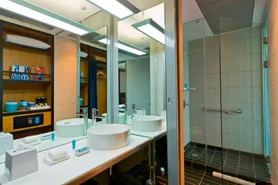 a bathroom with two sinks and a shower at Aloft San Jose Hotel, Costa Rica in San José