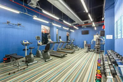 a gym with blue walls and treadmills and machines at Aloft San Jose Hotel, Costa Rica in San José