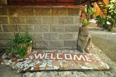 a welcome sign on a sidewalk in front of a brick wall at Howler Monkey Hotel in Montezuma