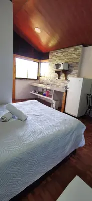 a bedroom with a large bed and a kitchen at Mora's Place B&B in Monteverde Costa Rica
