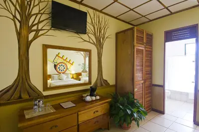 a room with a mirror and a bedroom with a bed at Adventure Inn in San José