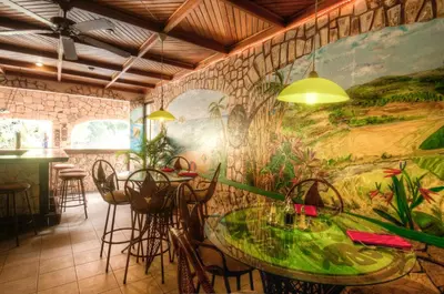 a restaurant with a table and chairs and a mural at Adventure Inn in San José