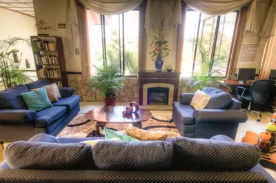 a living room with couches and a table and a fireplace at Adventure Inn in San José