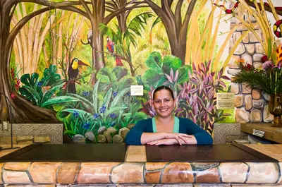 a woman sitting at a table in front of a mural at Adventure Inn in San José