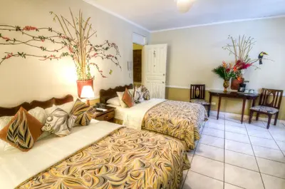 a hotel room with two beds and a table at Adventure Inn in San José