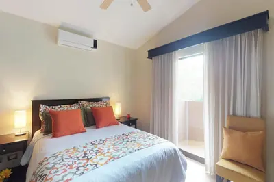 a bedroom with a bed with orange pillows and a window at The Cove 9/10 in Ocotal