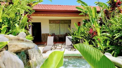 a garden with a waterfall and a house at Volcano Lodge, Hotel & Thermal Experience in Fortuna
