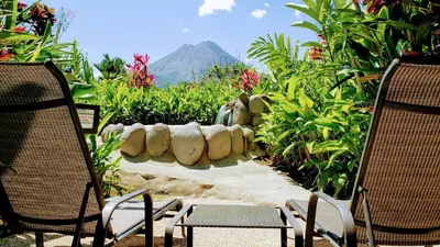 a garden with chairs and a mountain in the background at Volcano Lodge, Hotel & Thermal Experience in Fortuna