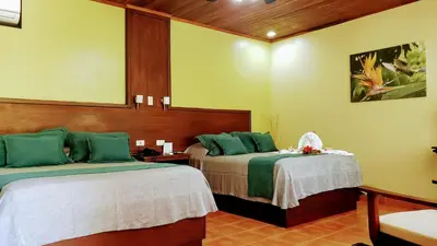 a bedroom with two beds with green and white sheets at Volcano Lodge, Hotel & Thermal Experience in Fortuna