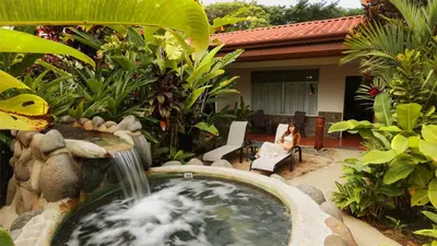 a woman sitting in a chair next to a water fountain at Volcano Lodge, Hotel & Thermal Experience in Fortuna
