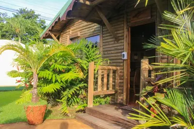 a small wooden cabin with a porch and some plants at Bungalows Ballena in Uvita