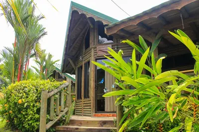 a small wooden house with a wooden porch and stairs at Bungalows Ballena in Uvita