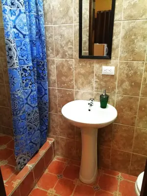 a bathroom with a sink and a blue shower curtain at Casa La Guaria in Sámara