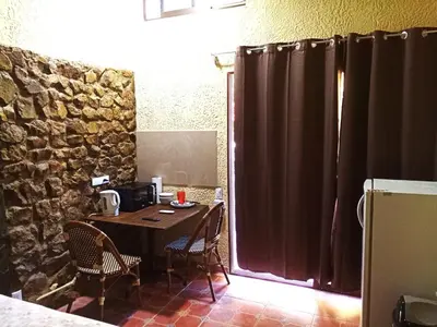 a table and chairs in a room with a stone wall at Casa La Guaria in Sámara
