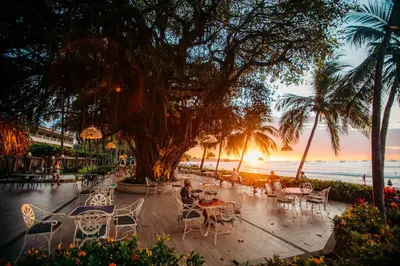 a group of tables and chairs on the beach at sunset at Hotel Tamarindo Diria Beach Resort in Tamarindo