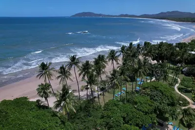 an aerial view of a beach with palm trees and the ocean at Hotel Tamarindo Diria Beach Resort in Tamarindo