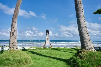 a woman standing on the beach between two palm trees at Hotel Tamarindo Diria Beach Resort in Tamarindo