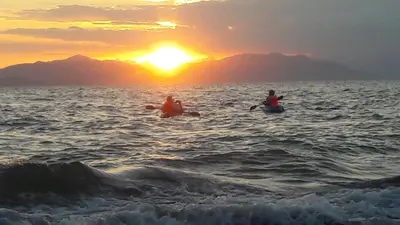 two people are in the water at sunset at Atardecer porteño in Puntarenas