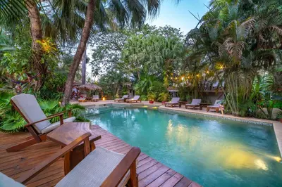 a swimming pool with chaise lounge chairs on a wooden deck at Hotel Pasatiempo in Tamarindo