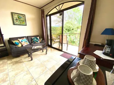 a living room with a couch and a large window at Hotel Vista Linda Montaña in Alajuela City