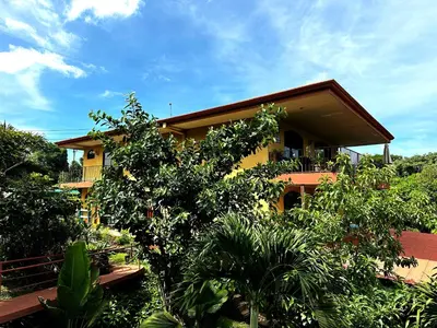 a yellow house with trees in front of it at Hotel Vista Linda Montaña in Alajuela City
