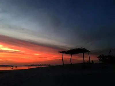 a sunset on the beach with an umbrella on the beach at Villa Tortuga in Nosara