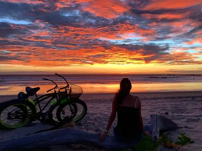 a woman sitting on the beach next to a bike at Villa Tortuga in Nosara