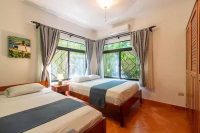 two beds in a room with two windows at Villa Tortuga in Nosara