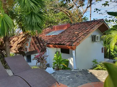 a small white house with a brown roof at Finca Los Caballos Montezuma in Montezuma