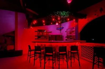 a bar with chairs in a room with red lights at Hotel El Icaco Tortuguero in Tortuguero
