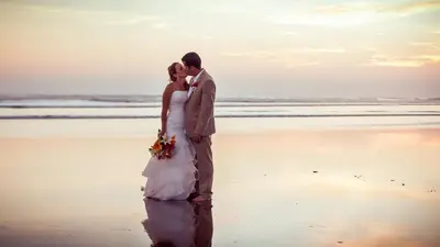 a bride and groom kissing on the beach at Alma del Pacifico Hotel & Spa in Esterillos Este