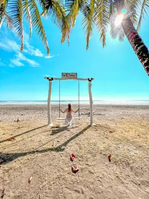 a woman sitting on a swing on a beach at Alma del Pacifico Hotel & Spa in Esterillos Este