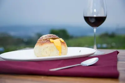 a piece of bread on a plate next to a glass of wine at Eco Granja Don Lolo in Quesada