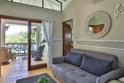 a living room with a couch and a mirror at Casa de Paz- Portasol Vacation Rentals in Matapalo