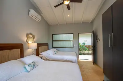 a bedroom with two beds and a ceiling fan at Casa de Paz- Portasol Vacation Rentals in Matapalo