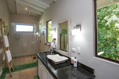 a bathroom with a sink and a mirror and a shower at Casa de Paz- Portasol Vacation Rentals in Matapalo