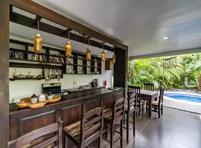 a kitchen and dining room with a bar and a swimming pool at Good Life Lodge in Sámara