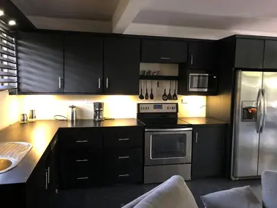 a kitchen with black cabinets and a stainless steel refrigerator at Good Life Lodge in Sámara