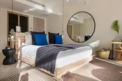 a bedroom with a large bed with blue pillows and a mirror at Hotel Nantipa - A Tico Beach Experience in Santa Teresa Beach